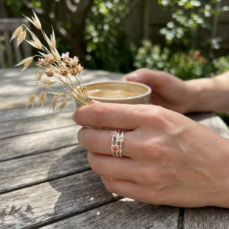Macro close-up of silver Oregon Sunstone Rainbow Ring with multicolored gemstones on rustic wooden surface.