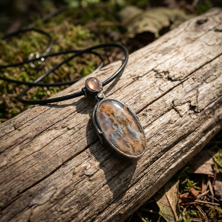 Close-up of the Sunstone Nebula necklace pendant showcasing intricate textures and celestial swirl patterns on silver and gemstones.