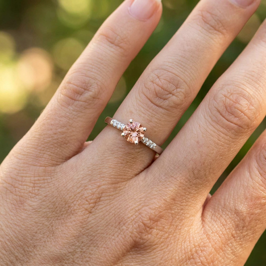 Close-up of the engagement ring on a textured neutral surface, highlighting fine craftsmanship and sparkling Oregon Sunstone.