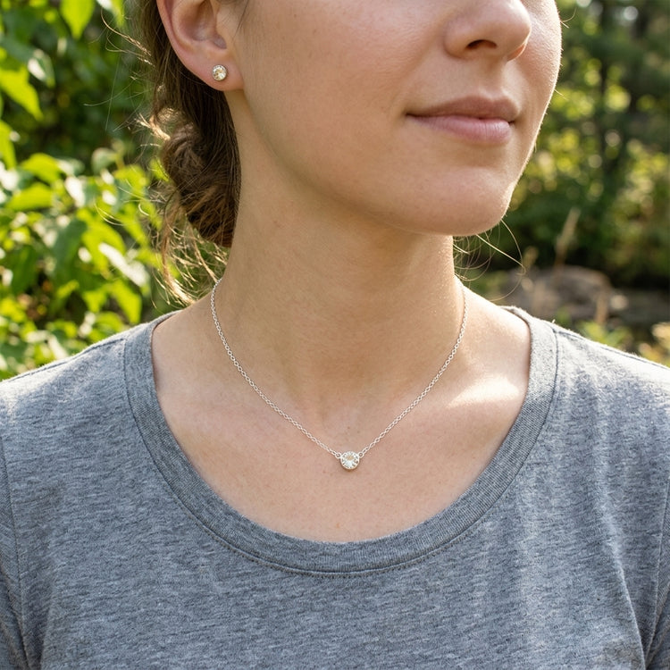 Female model outdoors in casual attire wearing a Sterling Silver Necklace with tiny Sunstone pendant on her collarbone.