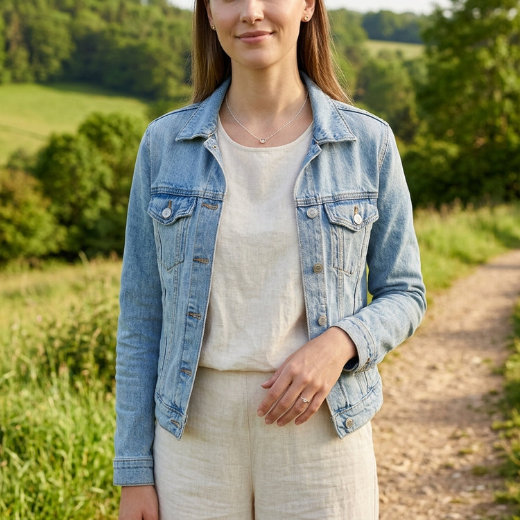 Female model outdoors wearing a simple sterling silver Sunstone necklace, with relaxed hand and natural background.