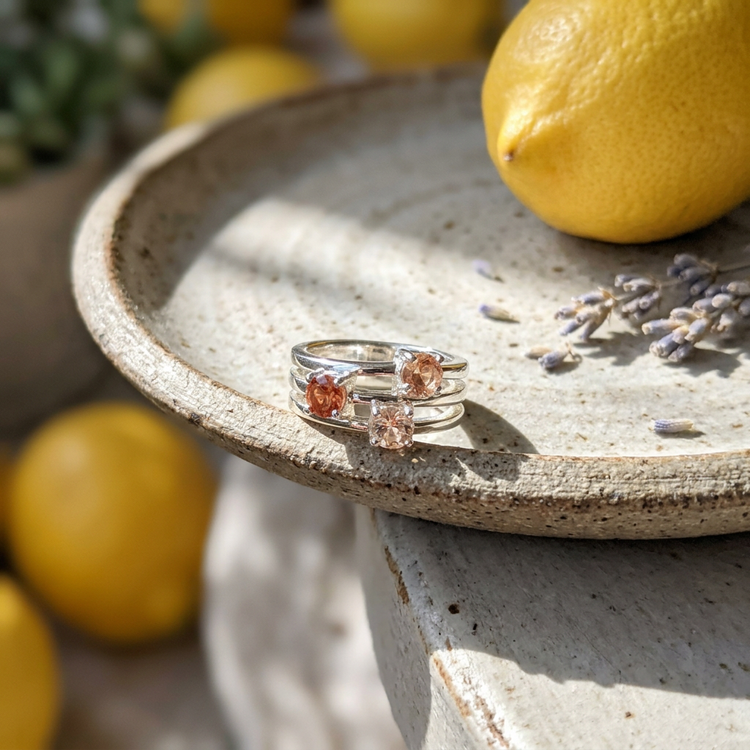 Overhead shot of silver Oregon Sunstone Rainbow Ring on textured fabric with pastel elements for casual elegance.