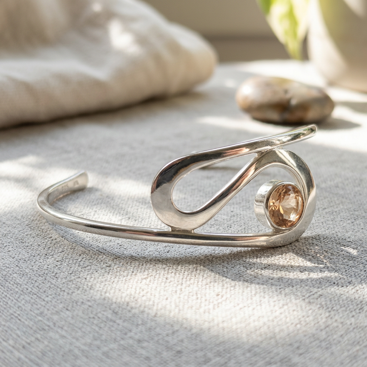 Side profile of the 'Ebb & Flow' sunstone cuff bracelet, emphasizing tapering width and micro-texture in bright natural sunlight.