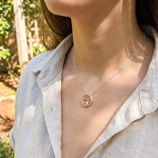 Close-up of Silver Oregon Sunstone Eclipse Necklace pendant with faceted sunstone set in sterling silver, showcasing brilliant facets and copper inclusions in natural outdoor setting.