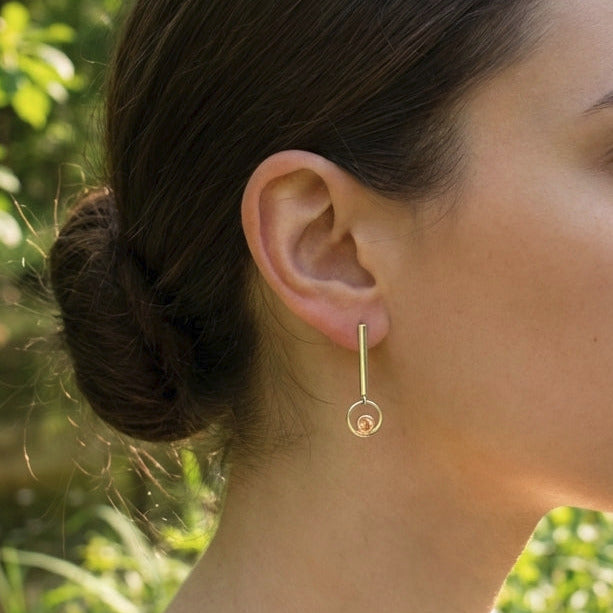 Side view of Sunstone Dangle Earring worn outdoors on a minimalist model, highlighting its length and peach glow in nature setting.