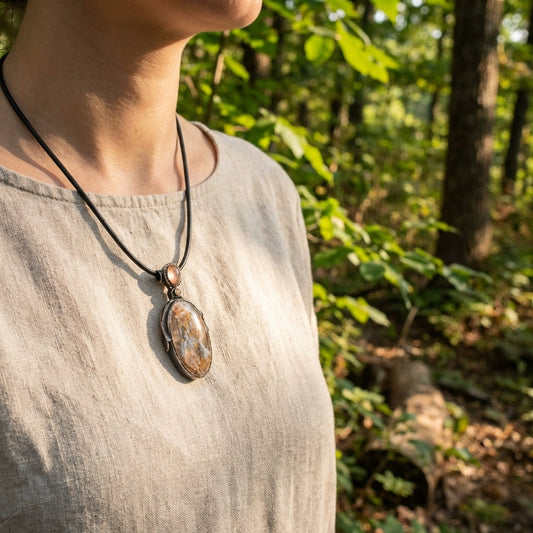 Full-body of person wearing the Sunstone Nebula necklace outdoors, highlighting handcrafted design and natural setting with greenery.