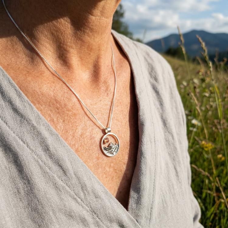 Casual outdoor scene with woman wearing sterling silver mountain necklace featuring Oregon Sunstone, natural sunlight highlighting textured details.