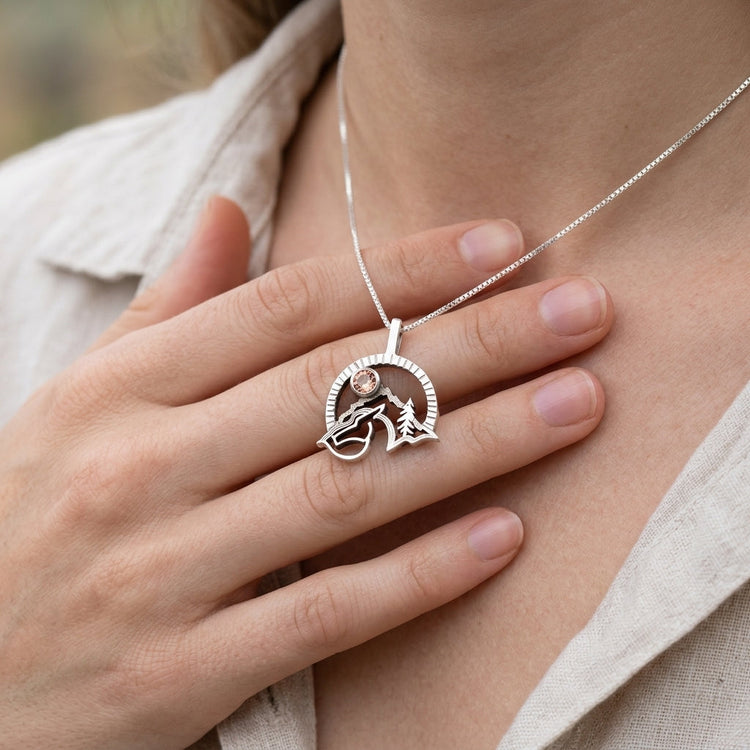 Overhead view of a polished silver horse pendant with Oregon Sunstone, showcasing delicate details and craftsmanship on a soft background.