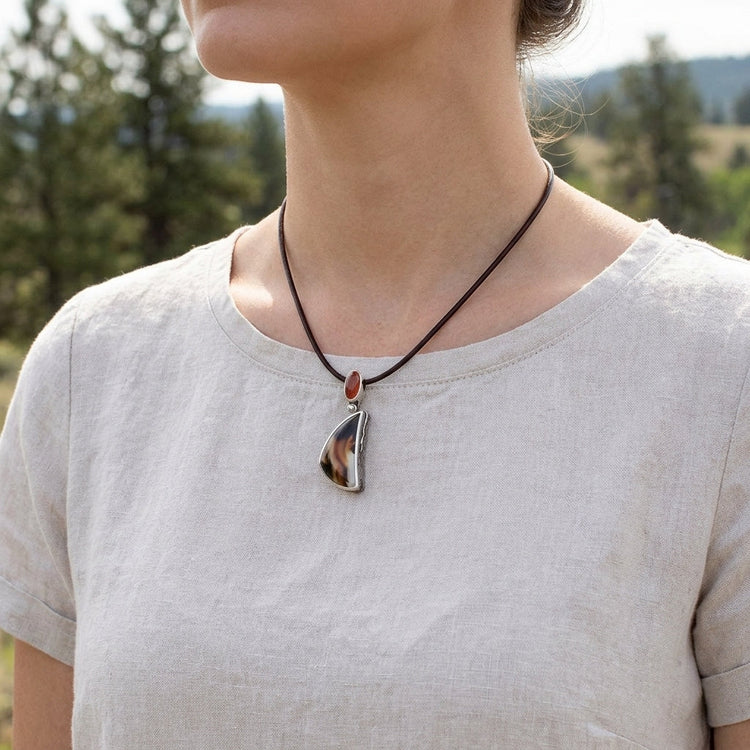 Female model outdoors wearing the Montana Agate and Sunstone pendant on a leather cord, in natural landscape with casual attire.