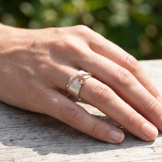 Hand wearing the Alya Star Oregon Sunstone Ring with silver and rose gold, captured outdoors with natural sunlight highlighting its elegance.