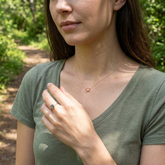 Female model outdoors wearing a delicate 6.5mm Peach Schiller Oregon Sunstone necklace in natural scenery.