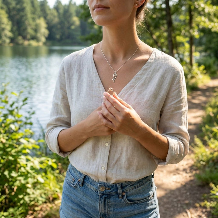 Full-body shot of woman in casual summer attire wearing the small 'Ebb & Flow' necklace with Sunstone near a serene lake.