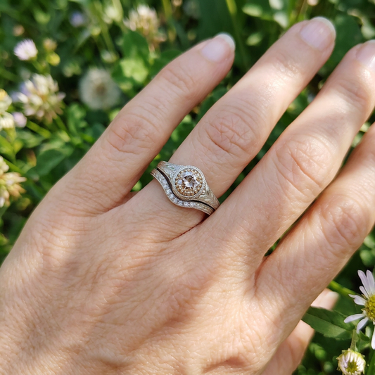 Close-up of a 14K white gold vintage wedding set featuring a .71ct Old Mine Cut diamond engagement ring and delicate wedding band with six small diamonds.