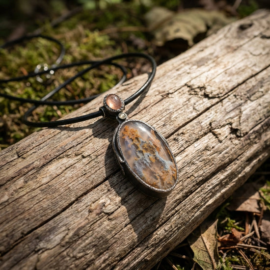 Close-up of the Sunstone Nebula necklace pendant showcasing intricate textures and celestial swirl patterns on silver and gemstones.