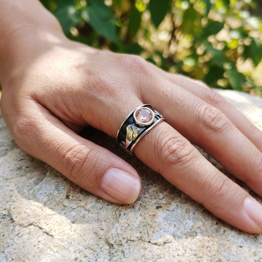 Close-up of a delicate Oregon Wonderland Engagement Ring with sunstone on a relaxed hand, natural outdoor setting, highlighting silver details and shimmer.