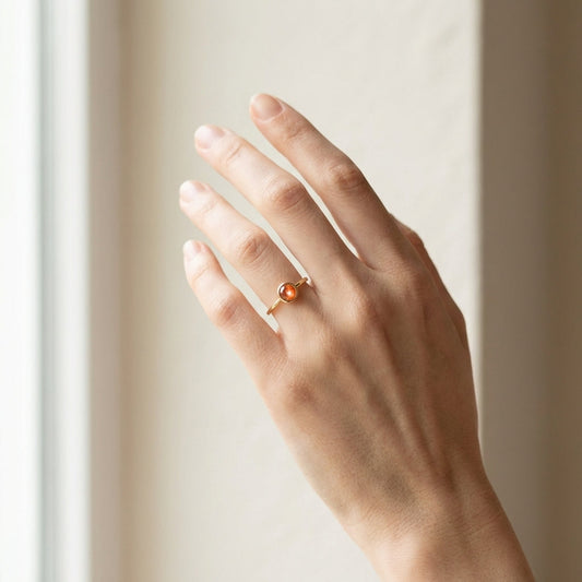 Full-body view of a petite 10K gold sunstone ring worn on a model’s finger against a minimal background, showcasing its smooth bezel and fiery shimmer.