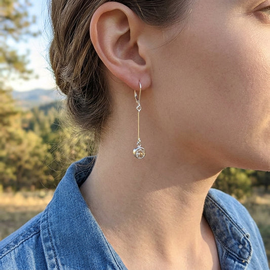 Female model in casual attire showcasing silver Champagne Sunstone modern bar earrings in a natural outdoor setting.