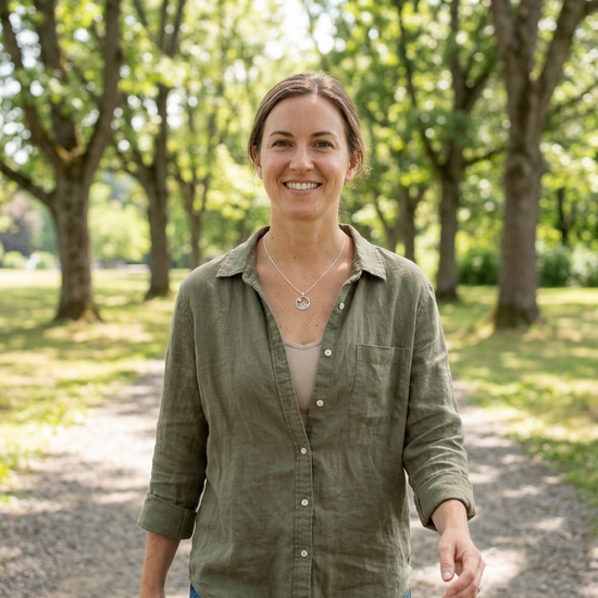 Person wearing sterling silver mountain necklace with Oregon Sunstone in outdoor natural setting, emphasizing delicate chain and textured pendant.