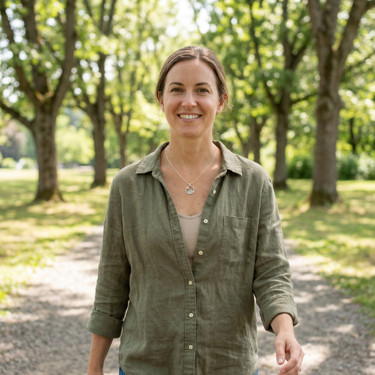 Person wearing sterling silver mountain necklace with Oregon Sunstone in outdoor natural setting, emphasizing delicate chain and textured pendant.
