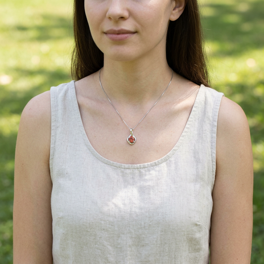 Model wearing infinity necklace with bright red sunstone pendant, captured outdoors in natural light with a casual spring background.