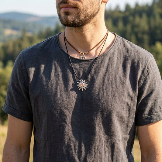 Male model in casual outdoor attire wearing a tiny silver sunburst pendant necklace, focused on the detailed craftsmanship against natural landscape.