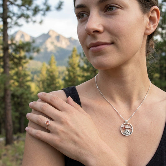 Full-body outdoor shot of a model wearing the Oregon Mountain Pendant necklace with pine trees and mountains in background.