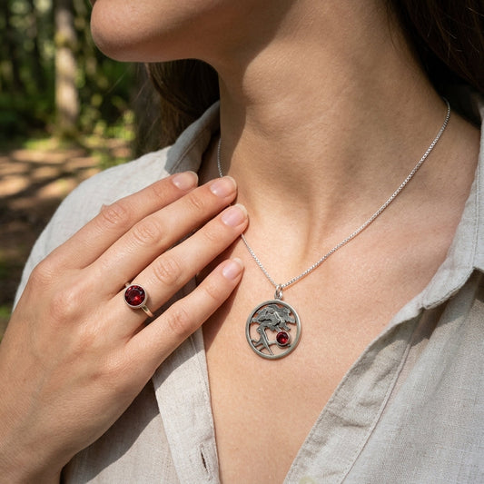 Side view of a relaxed model wearing a sterling silver Tree of Life medallion with Oregon Sunstone in a natural outdoor environment.