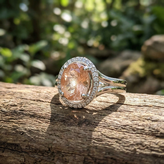 Close-up of the Sunstone Halo Ring on a wooden surface in natural sunlight, highlighting the peach hues and sparkling halo of lab diamonds.