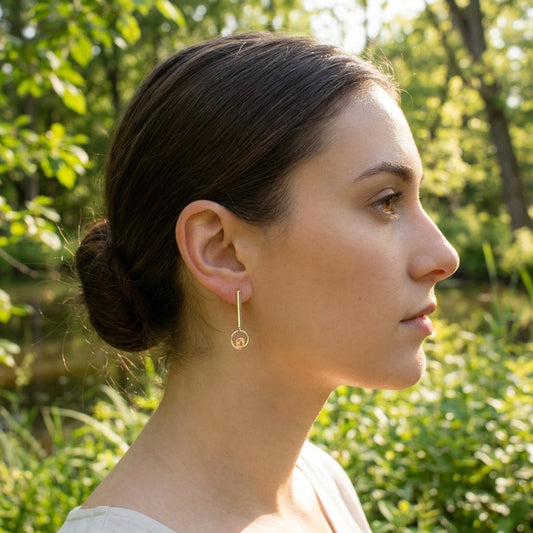 Side view of Sunstone Dangle Earring worn outdoors on a minimalist model, highlighting its length and peach glow in nature setting.